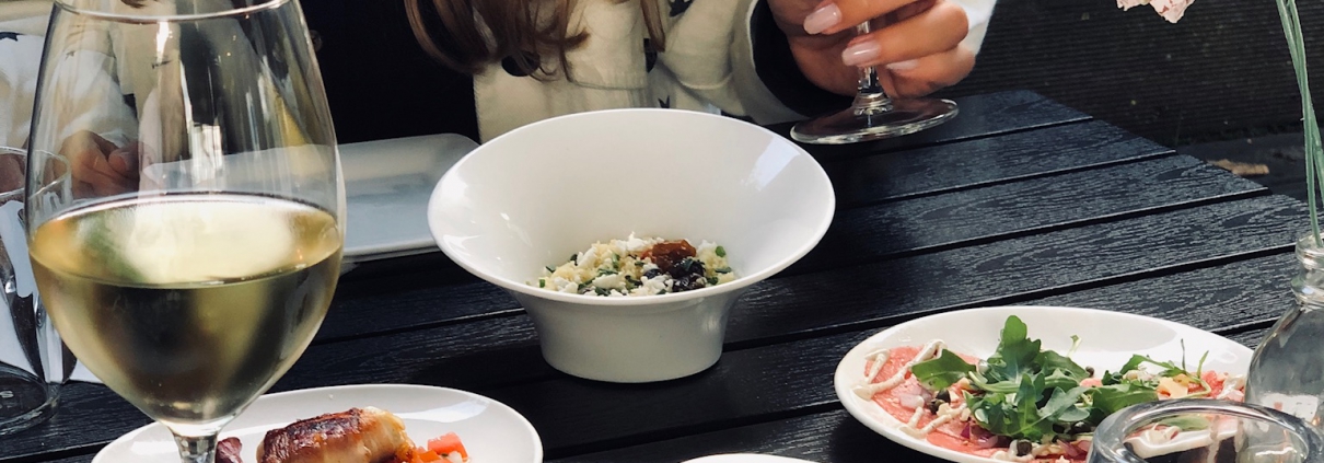 Gast met een glas wijn en tapasgerechtjes op het terras van Rodaen