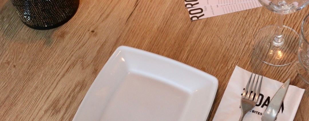 Gedekte tafel met bord, bestek en glazen bij Rodaen
